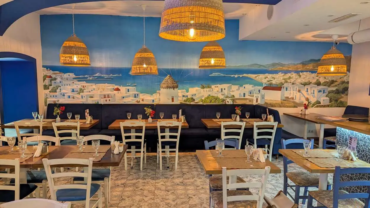 a mural with a view of Mykonos and sofas along the wall